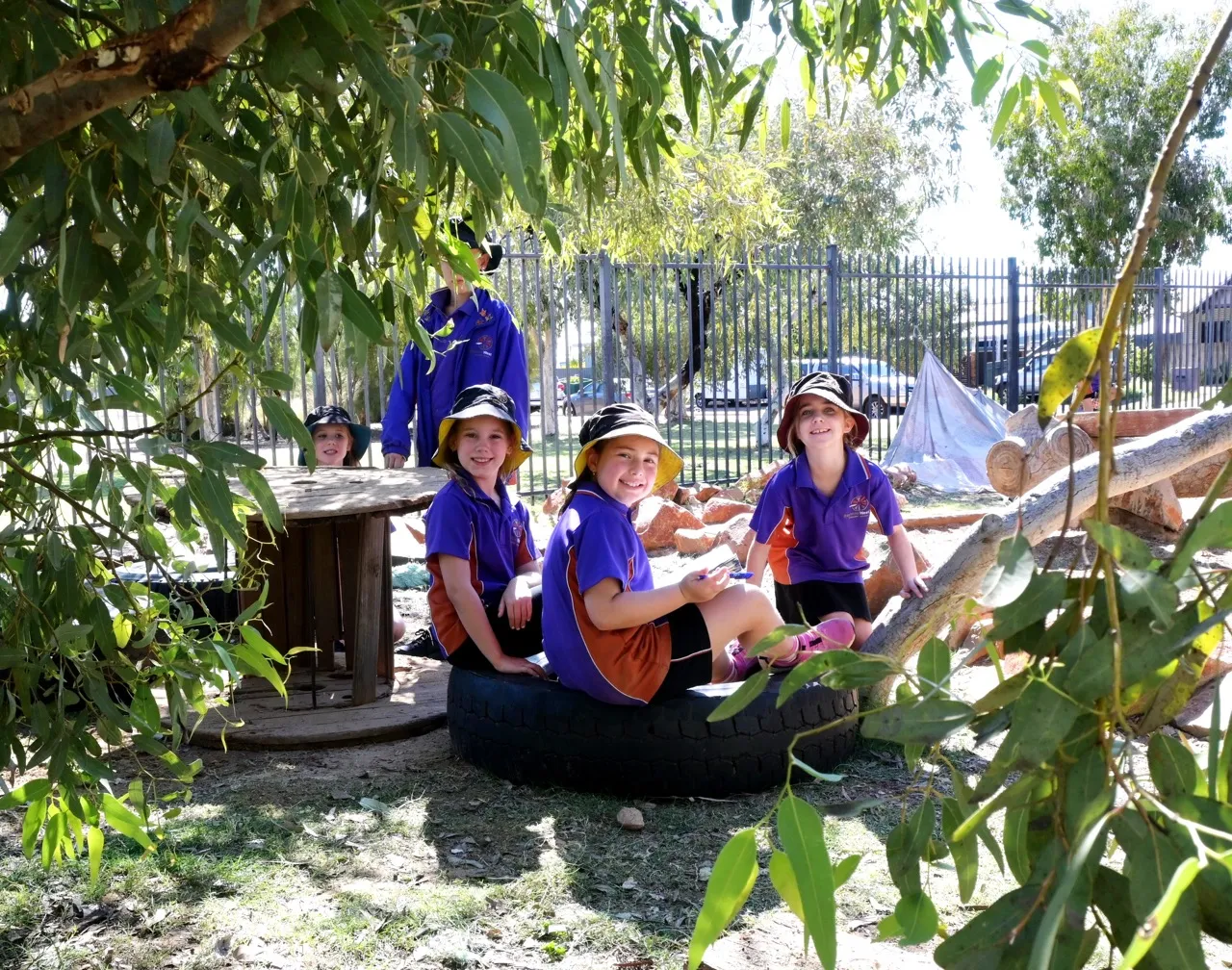 Students sitting on a tire looking at the camera